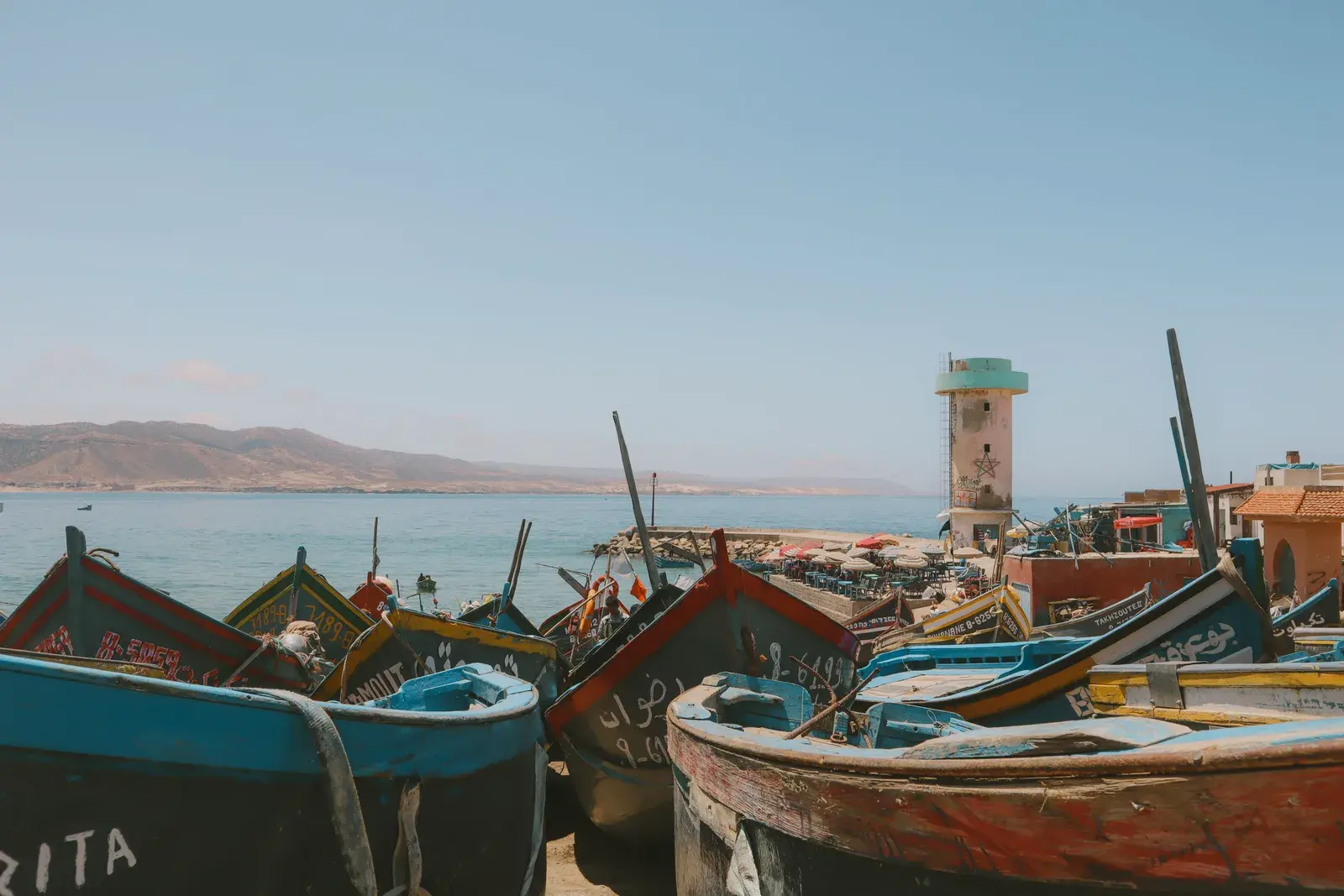 Colourful fishing boats in front of the lighthouse at Imsouane harbour, Morocco